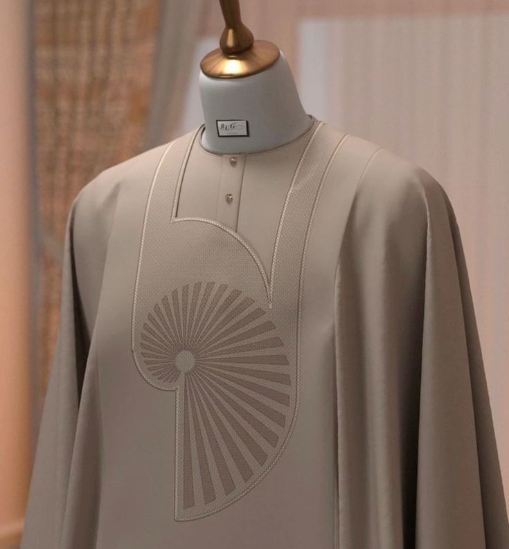 A sophisticated taupe Agbada with a unique spiral-fan embroidery concept.